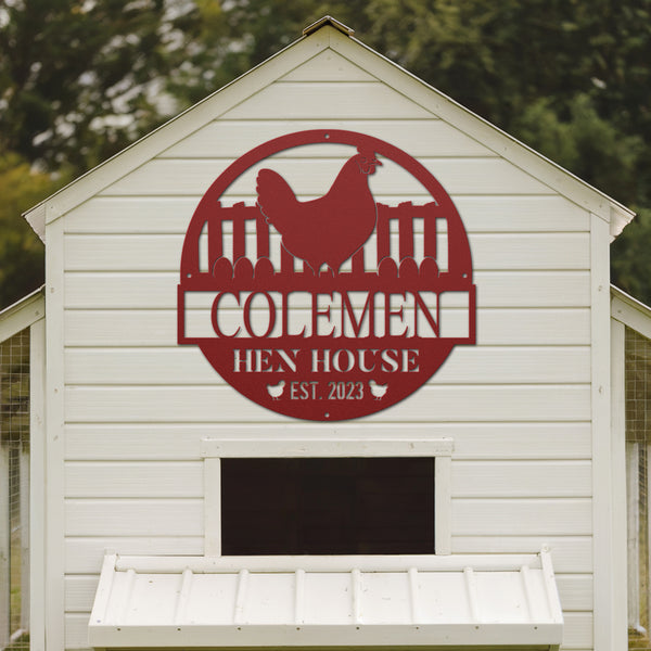 White chicken coop with a red 'Colemen Hen House' sign on a blurred green background