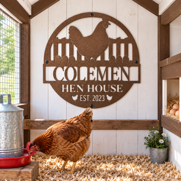 A personalized wooden chicken coop sign featuring a rooster silhouette and the cutout text 'COLEMEN HEN HOUSE EST. 2023' displayed on a white wood back wall inside a coop, with a brown hen walking in the foreground.