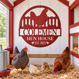 A red metal chicken coop sign reading 'CODEMEN HEN HOUSE EST. 2023' mounted on a white wood-paneled coop wall, with two hens and two chicks standing on straw bedding inside the coop.