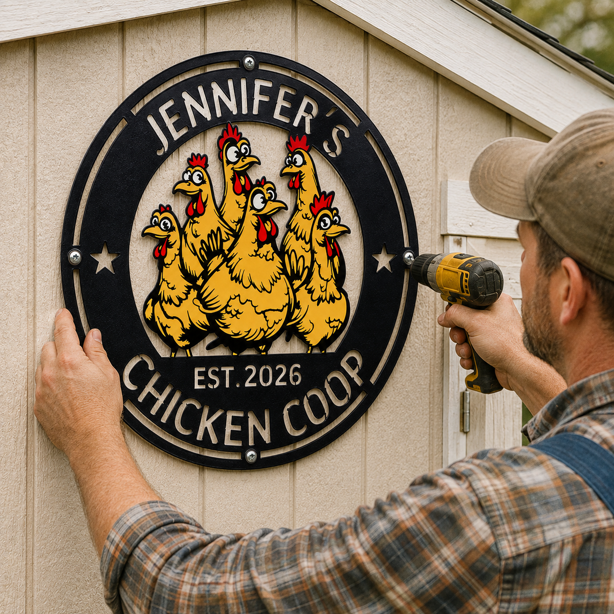 A man in a plaid shirt and cap uses a drill to install a circular metal sign that reads 'Jennifer's Chicken Coop' with cartoon chickens, mounted on a beige wooden shed wall.