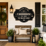 A decorative black metal sign reading “Welcome to Our Farmhouse Est. 2024 The Miller Family” hangs on a white shiplap wall above a rustic wooden bench with pillows, potted plants, and a porch lantern.