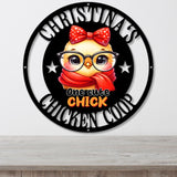 A circular black metal wall sign featuring a cartoon chick wearing a red polka-dot bow and red scarf, with the text 'CHRISTMAS CHICKEN COOP' and 'one cute CHICK' in white and orange lettering, shown hanging on a light gray wall above a wooden surface.