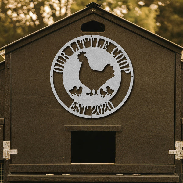 Brown chicken coop with a metal logo featuring a rooster and chickens, set against a blurred natural background.