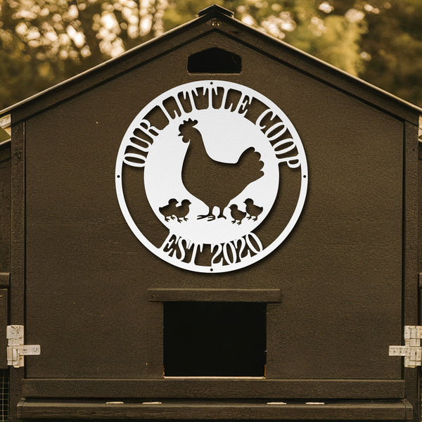 Brown chicken coop with a decorative metal plate featuring a rooster and chickens, set against a blurred natural background.