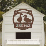 White chicken coop with 'Amanda's Quack Shack' sign featuring two ducks.
