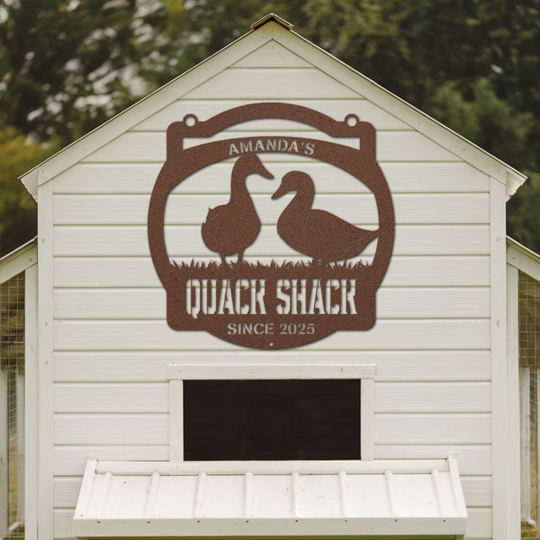White chicken coop with 'Amanda's Quack Shack' sign featuring two ducks.