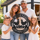 A family of four stands outdoors in front of a white and black farmhouse with chickens visible in the background, holding a large round black metal sign that reads “The Davis Family Chicken Coop Est. 2025” with chicken silhouettes.