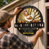 A man wearing a tan cap and plaid shirt hangs a decorative metal sign on a light wood chicken coop wall. The sign features a stylized chicken with brown and white feathers, yellow sunburst rays, three brown eggs, and the text 'THE MILLER FAMILY CHICKEN COOP EST.