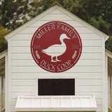 White duck coop with a red 'Miller Family Duck Coop' logo on a blurred green background