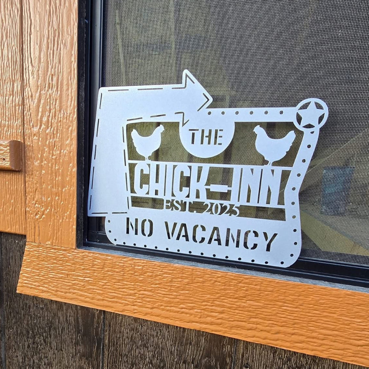 Decorative metal sign on a door with 'The Chick Inn' and 'No Vacancy' text.